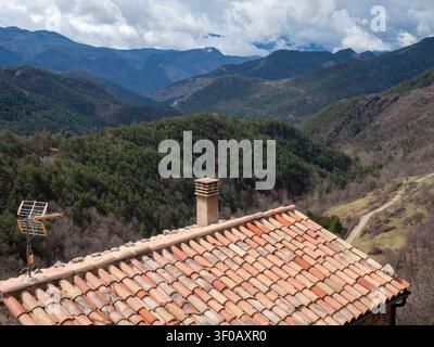 Une maison rurale rustique construite en pierre naturelle avec un toit de tuiles classique, dotée de pierres placées sur le dessus pour la protection contre le vent. Le bâtiment est situé dans Banque D'Images