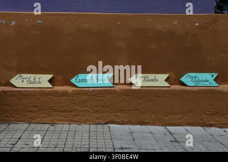 Panneaux directionnels colorés sur un mur texturé à Colonia del Sacramento, Uruguay Banque D'Images