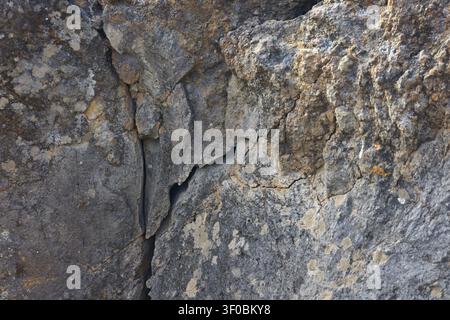 Photographie en gros plan détaillée d'une surface de roche volcanique fissurée montrant des textures naturelles, l'érosion et des motifs géologiques Banque D'Images