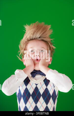 Enfant surpris en classe. Enfant drôle devant un fond de tableau vert. Concept de retour à l'école et d'éducation Banque D'Images