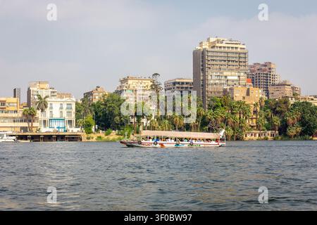Giza, Égypte, 25.07.21. Bateau touristique en bois Alhaga avec des gens naviguant sur le Nil avec le paysage urbain de Giza en arrière-plan. Banque D'Images