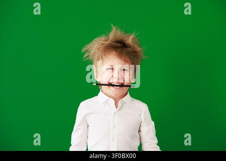 Enfant heureux en classe. Enfant drôle devant un fond de tableau vert. Concept de retour à l'école et d'éducation Banque D'Images