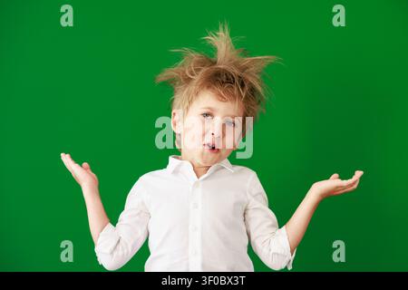 Enfant surpris en classe. Enfant drôle devant un fond de tableau vert. Concept de retour à l'école et d'éducation Banque D'Images