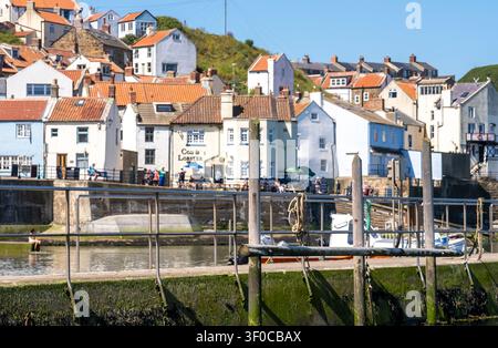 Focus sélectif sur la jetée en béton et les poteaux d'amarrage en bois du port de Staithes, avec un arrière-plan légèrement flou mettant en valeur la texture et la côte Banque D'Images