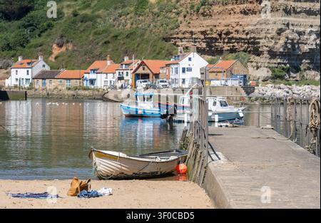 Petit bateau amarré à la jetée en béton du port de Staithes, capturé avec une mise au point sélective sur le premier plan et un arrière-plan légèrement flou pour la profondeur a Banque D'Images