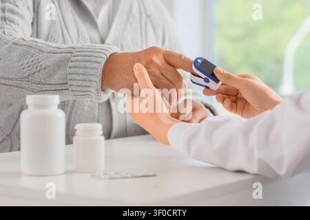 Professionnel de santé vérifiant le niveau d'oxygène des personnes âgées avec un oxymètre de pouls Banque D'Images