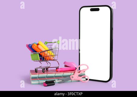 Smartphone avec panier et papeterie sur fond violet Banque D'Images