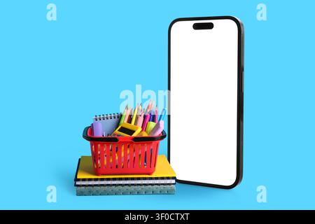 Smartphone avec écran vierge et panier de fournitures scolaires sur les cahiers Banque D'Images