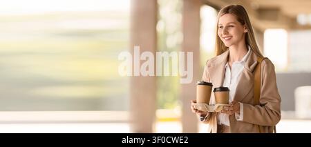 Jeune femme souriante tenant des tasses à café à emporter à l'extérieur Banque D'Images