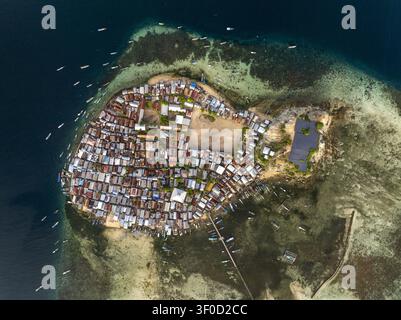 Vue aérienne du village de l'île de Pulau Mesa avec des logements denses, une zone centrale ouverte et de petits bateaux amarrés dans les eaux turquoises environnantes de Kecama Banque D'Images