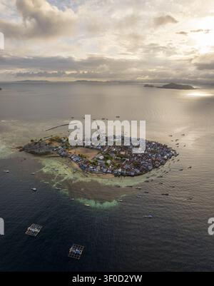 Vue aérienne du village de l'île de Pulau Mesa avec des maisons denses, des jetées en bois et des bateaux de pêche entourés par les eaux turquoises à Kecamatan Komodo, Nusa T. Banque D'Images