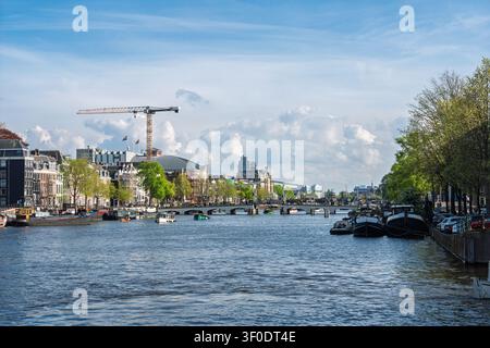 Vue pittoresque sur le fleuve Amstel avec une architecture historique et des bateaux à Amsterdam, Pays-Bas Banque D'Images