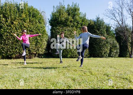 vue grand angle de trois personnes s'exerçant ensemble dans le parc par une journée ensoleillée Banque D'Images
