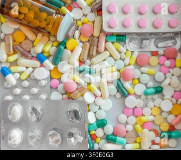 Texture en plein cadre à angle élevé de pilules, comprimés et capsules médicaux renversés avec une bouteille sombre Banque D'Images