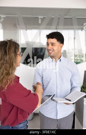 Collègues d'affaires souriants se serrant la main dans un bureau d'entreprise Banque D'Images