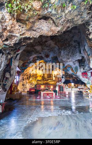 Ipoh, Malaisie – 28 juin 2026 : Statue géante de Bouddha doré à l'intérieur de la grotte calcaire du temple Perak Cave avec des peintures murales, Ipoh, Malaisie. Banque D'Images