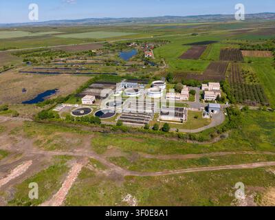 Une usine de traitement de l'eau est située dans un paysage verdoyant. Des champs, des étangs et des arbres environnants sont visibles. L'accent est mis sur le grand réservoir circulaire Banque D'Images
