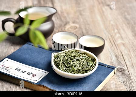 Cérémonie du thé vert traditionnel chinois avec des feuilles séchées et du thé infusé sur une table en bois rustique Banque D'Images