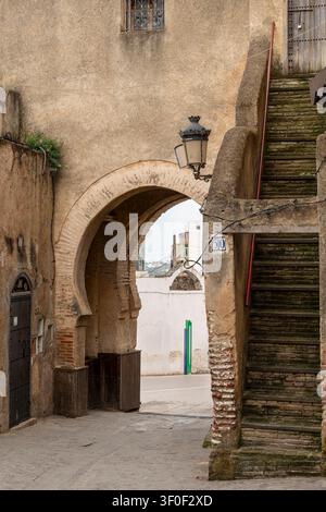 La porte Bab Saida présente trois arches consécutives en fer à cheval enjambant une rue de médina, avec des lanternes décoratives en fer forgé suspendues entre elles. Banque D'Images