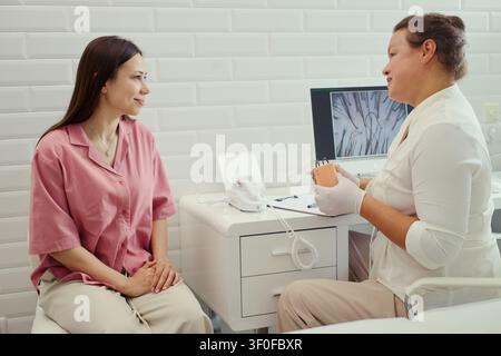 Jeune femme caucasienne consultant une dermatologue dans une clinique, discutant de l'examen de la peau et des options de traitement. Utile pour le marketing dans le domaine de la santé, la promotion des soins aux patients Banque D'Images