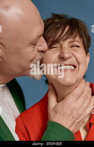 Un couple de personnes âgées joyeux profite d'un moment tendre tout en portant des tenues élégantes et colorées. Banque D'Images