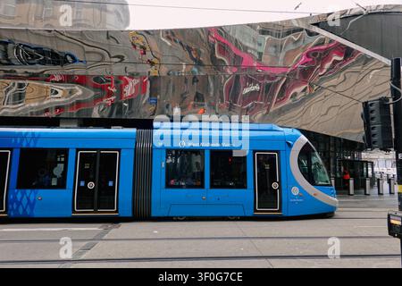 Tramway West Midlands Metro passant devant la façade réfléchissante de la gare de Birmingham New Street, Royaume-Uni Banque D'Images