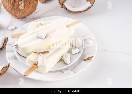 Popsicles au coco végétaliens sans produits laitiers. Lollies glacés diététiques avec crème ou lait de coco, dessert d'été glacé et sucré Banque D'Images