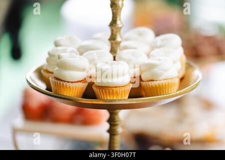 Mini cupcakes à la vanille avec glaçage au beurre blanc sur un support doré Banque D'Images