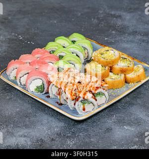 Une assiette remplie d'une variété de sushi et de rolls, soigneusement disposés sur une table. Banque D'Images