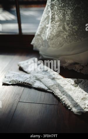 Manches d'une robe de mariée en dentelle blanche sur un sol en bois sombre Banque D'Images