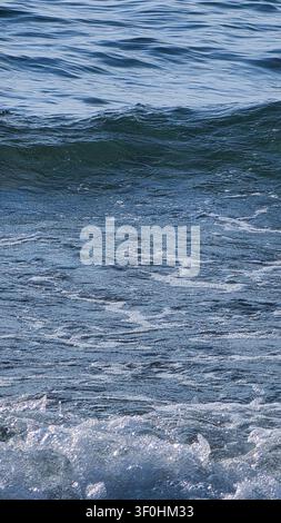 Vue rapprochée détaillée des vagues de l'océan en mouvement avec de l'écume blanche et une surface de l'eau ondulante pendant la journée. Banque D'Images