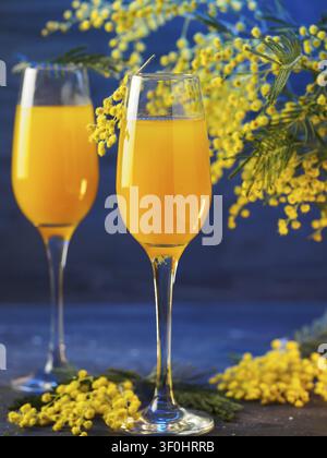 Cocktail mimosa et fleurs sur un fond bleu Banque D'Images