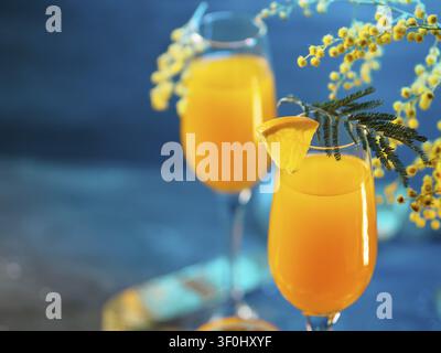 Cocktail mimosa et fleurs sur un fond bleu Banque D'Images