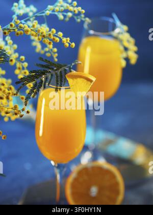 Cocktail mimosa et fleurs sur un fond bleu Banque D'Images