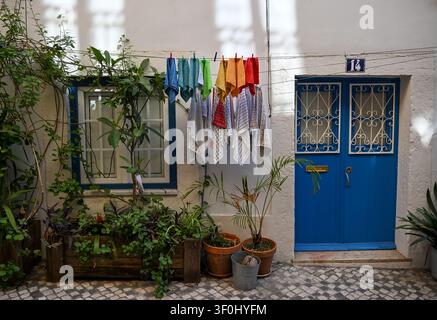Lessive colorée suspendue devant une porte bleue traditionnelle à Lisbonne, Portugal Banque D'Images