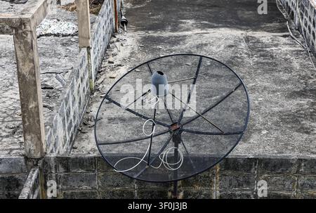 Antenne de communication par satellite abandonnée ou cassée sur le toit d'un vieux bâtiment. Banque D'Images