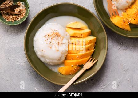 Riz collant thaïlandais au mangue dans du lait de coco avec graines de sésame grillées. Vue de dessus. Mise au point sélective Banque D'Images