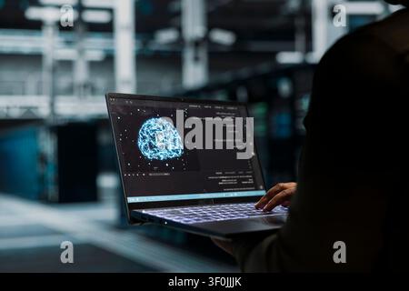 L'administrateur du centre de données utilise un ordinateur portable pour gérer les charges de travail d'apprentissage automatique, en travaillant avec la technologie IA et les systèmes haute performance. Banque D'Images