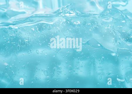 Image macro en gros plan mettant en valeur la texture complexe d'un gel bleu clair avec de nombreuses bulles d'air. La surface lisse et brillante capte la lumière, met en valeur Banque D'Images