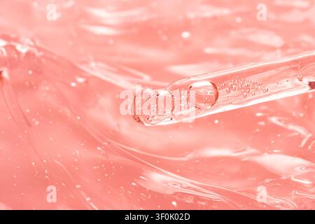 Une vue macro détaillée montrant une pipette transparente immergée dans un gel rose. L'image met en évidence la texture lisse du gel et les bulles en suspension, communique Banque D'Images