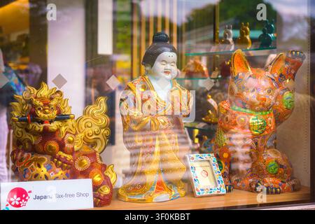 Kanazawa, Japon – 6 oct. 2024, vue rapprochée d’une vitrine avec des figurines en porcelaine de Maneki Neko, le dieu Hotei et Komainu, toutes peintes à la main et dorées Banque D'Images