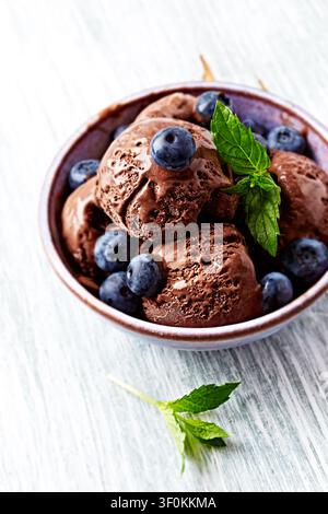 Glace au chocolat avec myrtilles et menthe fraîche. Arrière-plan en bois. Gros plan. Banque D'Images