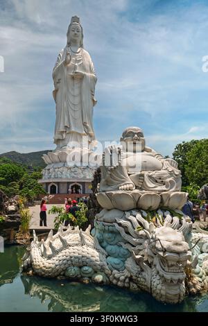 Da Nang, Vietnam - 29 avril 2026 : L'emblématique statue de la Dame Bouddha se dresse derrière une sculpture du Bouddha riant montée sur une fontaine dragon au complexe pittoresque de la pagode Linh Ung Banque D'Images