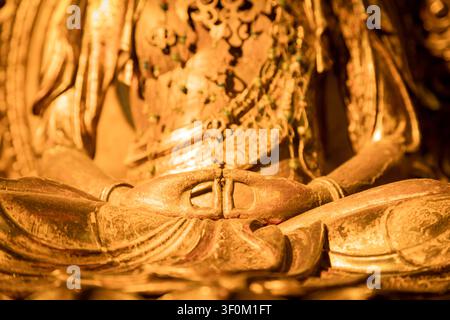 Gros plan d'une statue de Bouddha dorée montrant des mains détaillées dans le mudra de méditation, symbolisant la paix, la spiritualité et l'illumination avec ornam complexe Banque D'Images