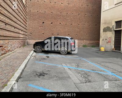 Cremona, Italie, 19 juin 2026 Voiture SUV Kia Sorento noire sur une rue européenne étroite. Architecture distinctive de vieux murs en briques et environnement urbain Banque D'Images