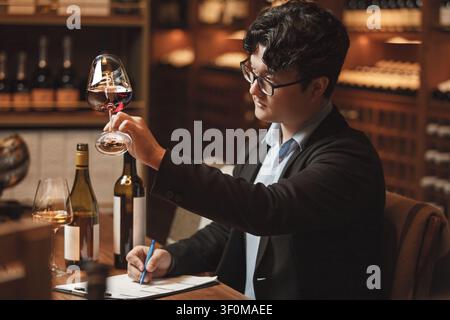 Sommelier professionnel dirige une dégustation de vin assis à une table dans la cave. Banque D'Images