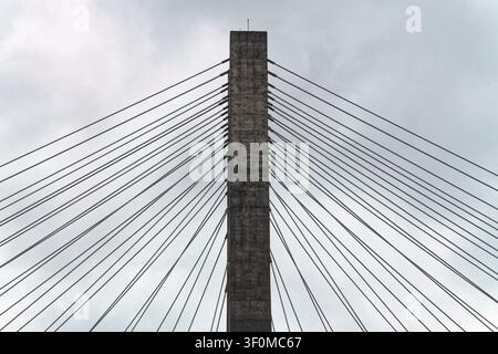 Vue abstraite en gros plan des câbles d'une passerelle à haubans rayonnant depuis un pilier en béton Banque D'Images