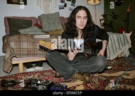 Portrait d'un homme aux cheveux longs jouant de la guitare électrique dans son studio à domicile Banque D'Images