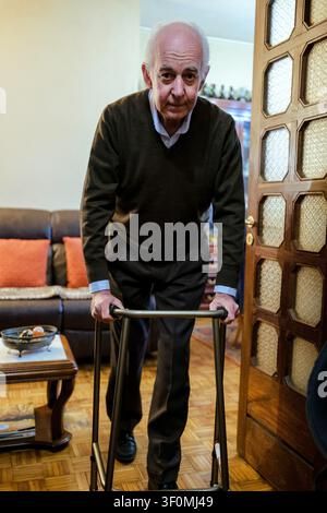 Homme âgé marchant lentement avec l'aide d'une canne à roulettes dans sa maison Banque D'Images