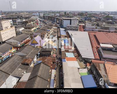 Vue aérienne du marché ferroviaire de Maeklong avec un train approchant sur les voies bordées de rangées denses d'étals de marché colorés et de toits à Mae Klong, S Banque D'Images